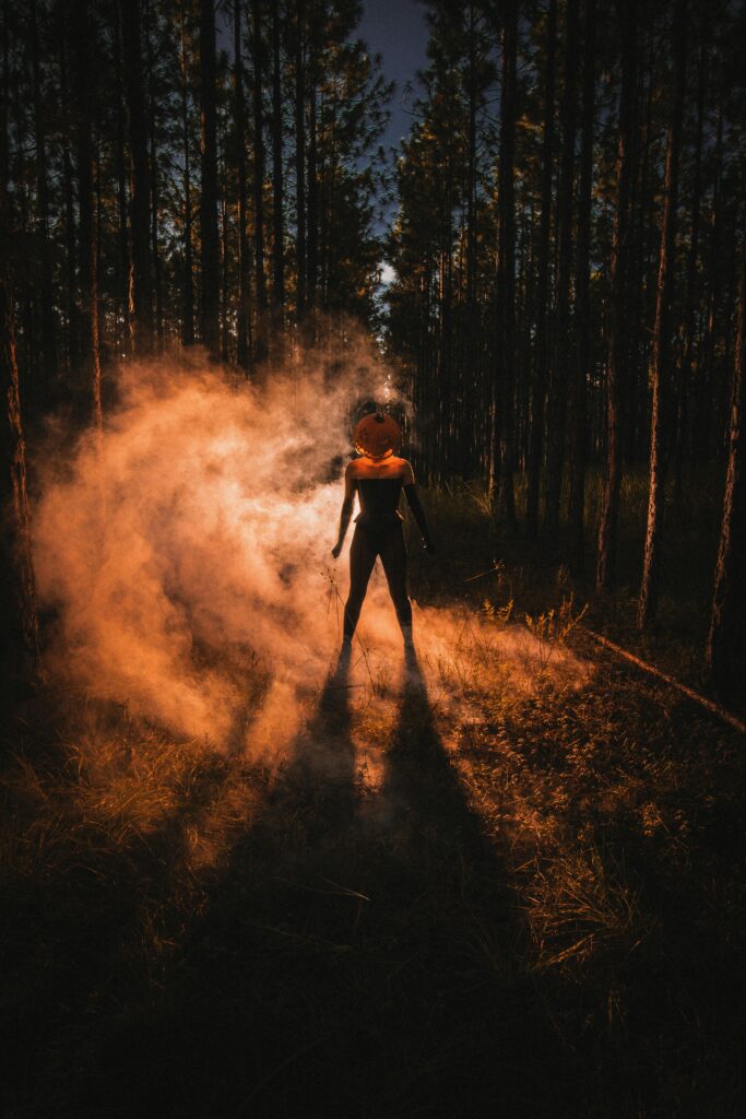 Silhouette of a person with a pumpkin head in a misty forest during Halloween in Orlando.