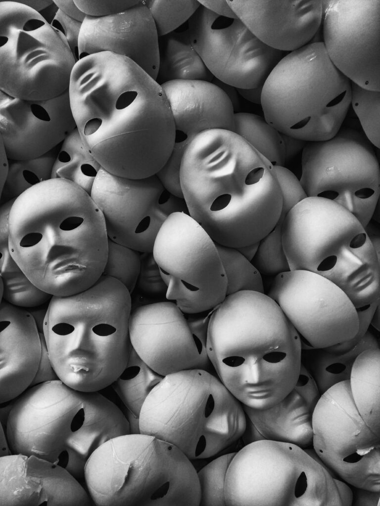 Black and white photo of numerous expressionless masks stacked together, creating an eerie atmosphere.
