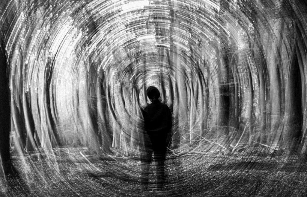 The 3:33 A.M. Pattern in Crime Logs Abstract black and white image of a person in a spinning forest, evoking mystery.