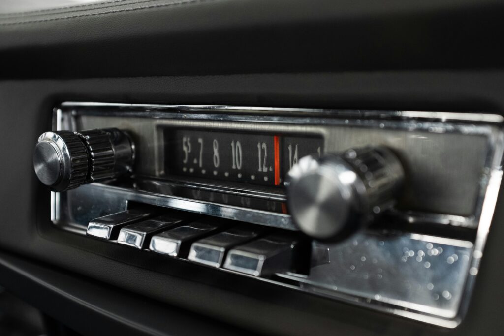 Detailed view of a classic car radio dashboard with chrome knobs and buttons.